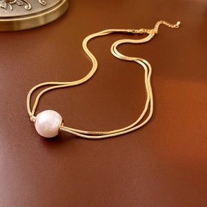 Detail of gold-plated double-layer snake chain necklace with a large white pearl pendant