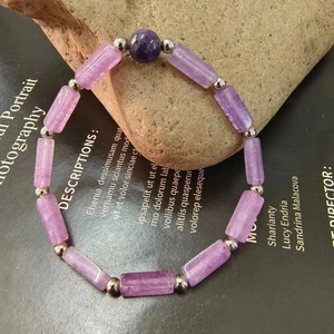 Close-up of amethyst beaded bracelet with cylindrical purple stones and silver spacers