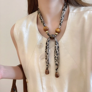Collier foulard léopard avec perles en résine ambre et pendentif goutte sur le cou