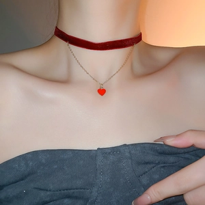 Detail of burgundy velvet choker with golden chain and a red heart pendant