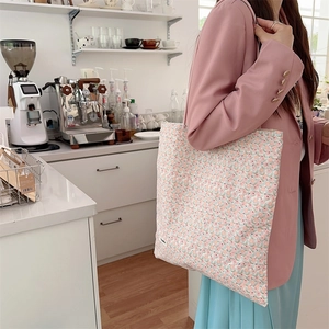 Vue détaillée d'un sac cabas en toile fleurie porté par un mannequin dans un café
