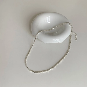 Collier argenté minimaliste avec perles carrées géométriques sur plateau blanc