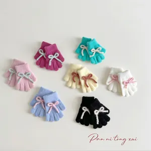 Detail view of colorful knitted kids gloves with contrast bows in seven soft colors