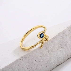 Detail of 18K gold plated evil eye ring with blue enamel charm on textured stone