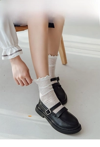 Nahaufnahme von weißen Spitzen-Socken mit Rüschenkante und schwarzen Mary-Jane-Schuhen