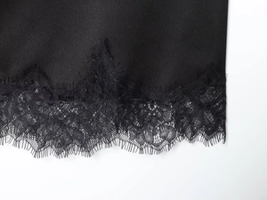 Detailed view of black satin fabric with delicate eyelash lace trim and refined stitching