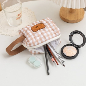 Detail of light brown checkered quilted vanity bag with embroidered teddy bear and handle