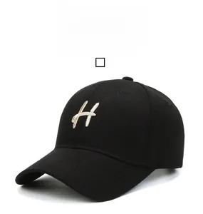 Detailed close-up of beige embroidered H letter on a classic black cotton baseball cap
