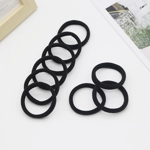 Detail of 10 black seamless high elasticity hair ties arranged on a clean white surface