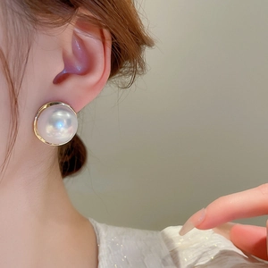 French vintage round pearl earrings with gold metallic edges worn by a female model