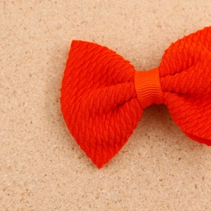 Close-up of bright orange-red textured bubble fabric hair bow with ribbed tie center