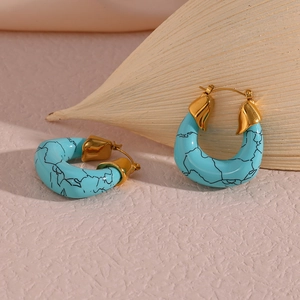 Detailed macro of gold-plated hoop earrings with turquoise marble texture finish