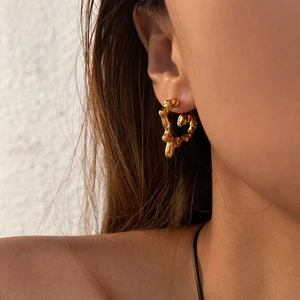Boho melted heart gold earrings with irregular lava texture worn by a model