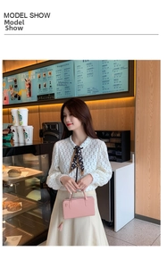 Pink faux leather crossbody bag with tassel detail shown by a model in a cafe setting