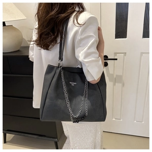 Detail of black tote bag with silver chain and bead decoration in a minimalist home setting