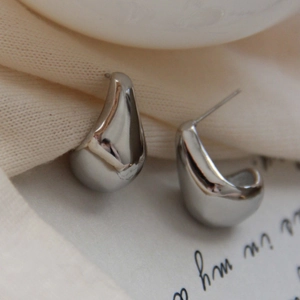 Macro shot of polished silver teardrop stud earrings with smooth metallic mirror finish