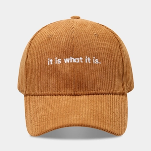 Dettaglio del cappello in velluto a coste marrone con ricamo bianco 'it is what it is'