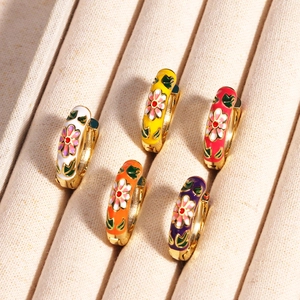 Detail von fünf goldenen Creolen mit bunten Emaille-Blumen und Blattmustern auf einem Tablett