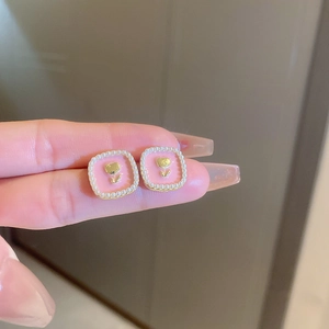 Close-up of square pink enamel earrings with gold tulip relief and pearl frame decoration