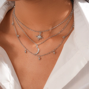 Detailed close-up of a silver-tone layered necklace featuring star and moon pendants