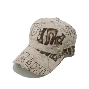 Close-up of beige canvas baseball cap with distressed details and brown letter print