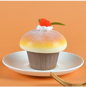 Macro shot of faux chocolate cupcake with white cream and red berries on orange background