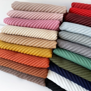 Close-up of stacked pleated scarves in multiple vibrant colors on a white background