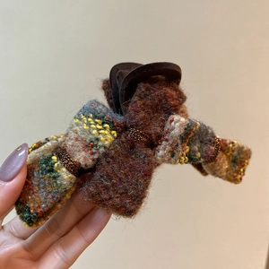 Close-up of retro plaid tweed claw clip in brown and yellow woven fabric textures