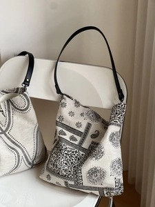 Detail of vintage linen tote bag with black paisley patterns and leather handles