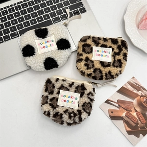 Three plush heart-shaped coin purses in cow and leopard prints on an aesthetic desk