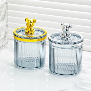 Detail of transparent storage jars with vertical textures and gold and silver bear lids