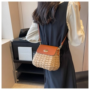 Detail showing the brown faux leather flap and gold twist lock on the handmade straw bag