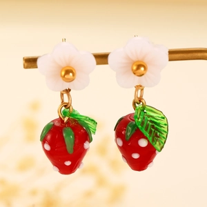 Detail of sweet strawberry and white flower earrings with gold metal hanging on a stand