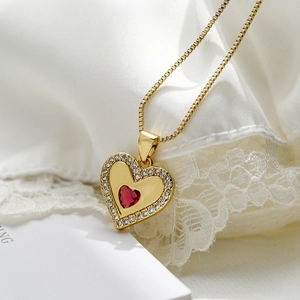 Close-up of gold plated heart pendant with red zircon and sparkling white micro-pave setting