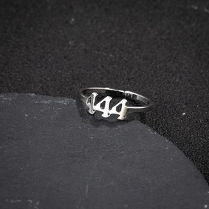 Macro shot of silver stainless steel 444 angel number ring on a black stone base