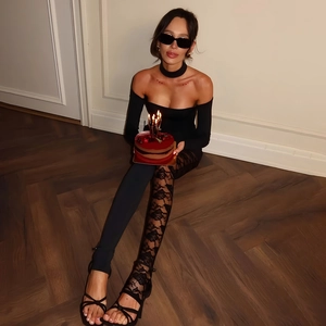 Detail of asymmetric black lace leggings and off-shoulder bodysuit on a fashion model
