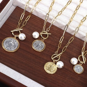 Detailed shot of gold paperclip chain necklaces with religious medals and pearls