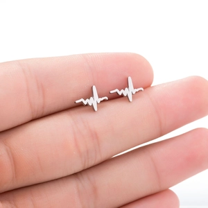 Macro shot of silver heartbeat pulse ear stud held between fingers for size reference