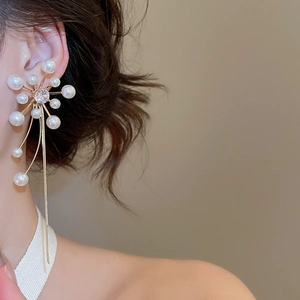 Detailed close-up of zircon flower earrings with long gold tassel and white pearls