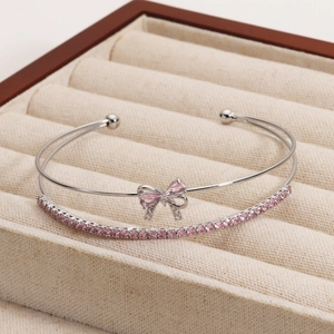 Double-layered silver bangle with pink zircon bow and sparkling tennis chain detail