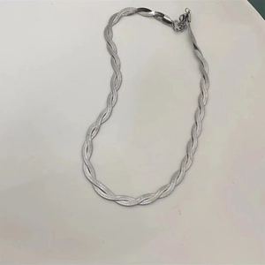 Macro detail of silver layered herringbone snake chain necklace with woven metallic texture