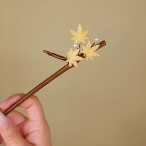 Close-up of wooden hair pin with golden maple leaves and delicate pearls