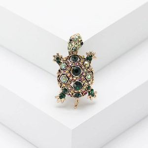 Vintage turtle brooch with green gemstones and colorful rhinestones on a gold base