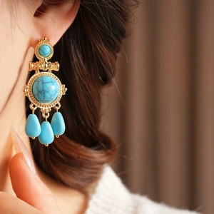 Detail view of vintage bohemian turquoise teardrop earrings with gold plating on model