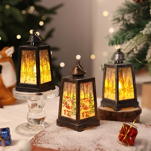 Three decorative Christmas lanterns with LED candles and festive scene prints on a table
