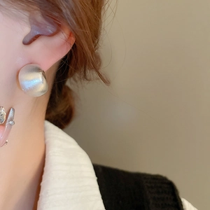 Close-up of a brushed silver C-shaped stud earring worn on a model's ear