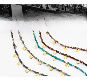 Detail of colorful stone beaded necklaces with gold circular pendants in varied colors