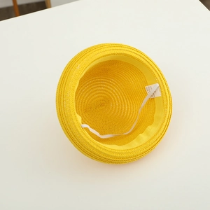 Détail du chapeau de soleil en paille jaune avec étiquette 100 % papier et mentonnière