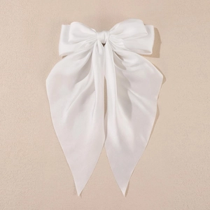 Close-up of white satin bow hair clip with elegant long ribbons and silky texture
