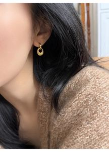 Nahaufnahme eines goldenen ovalen Ohrrings mit Hammerschlag-Struktur am Ohr eines Models